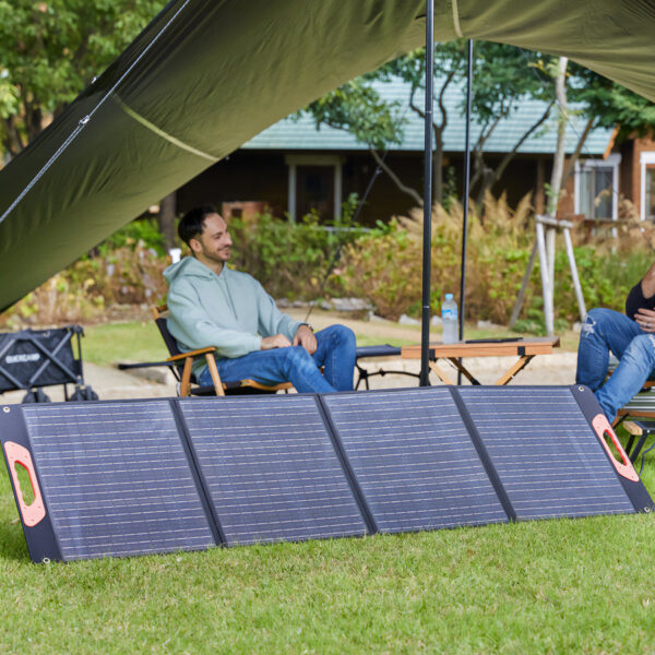 A-man-using-a-portable-power-source-and-solar-panels-outdoors